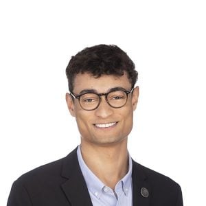 a man with black rimmed glasses smiles at the camera