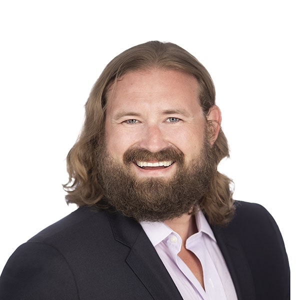 a man with long hair and a beard smiles at the camera