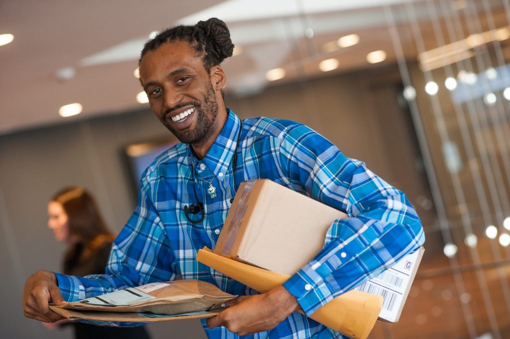 man holding parcels smiles at the camera