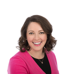 a woman in a pink sweater and black shirt smiles at the camera