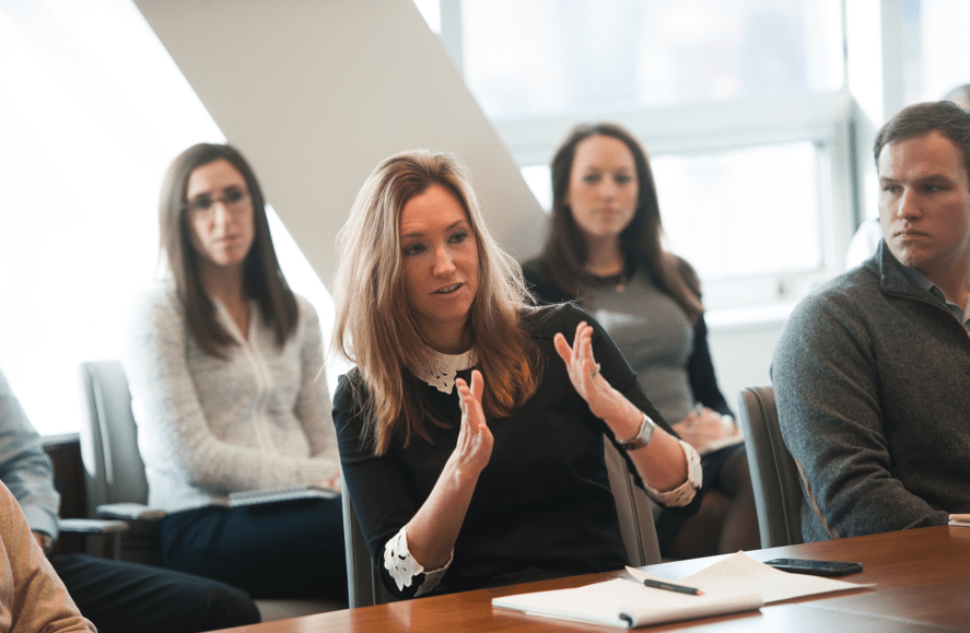 a woman in a black blouse is explaining something at a meeting