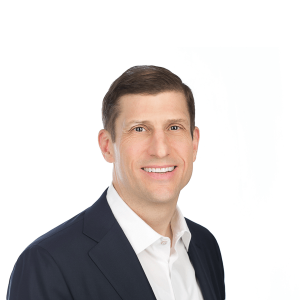 a man with brown hair wearing a black jacket and white shirt smiles at the camera