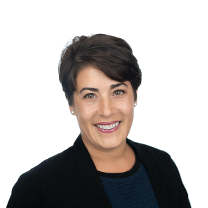 a woman with short brown hair wearing a black jacket and navy blue sweater smiles at the camera