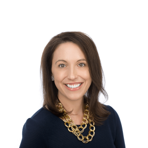 brown haired woman in a golden black shirt necklace smiles at the camera