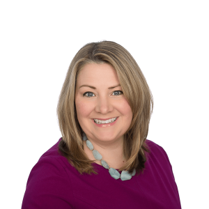 a woman with fair hair wearing a gray stone butcher wearing a burgundy blouse smiles at the camera