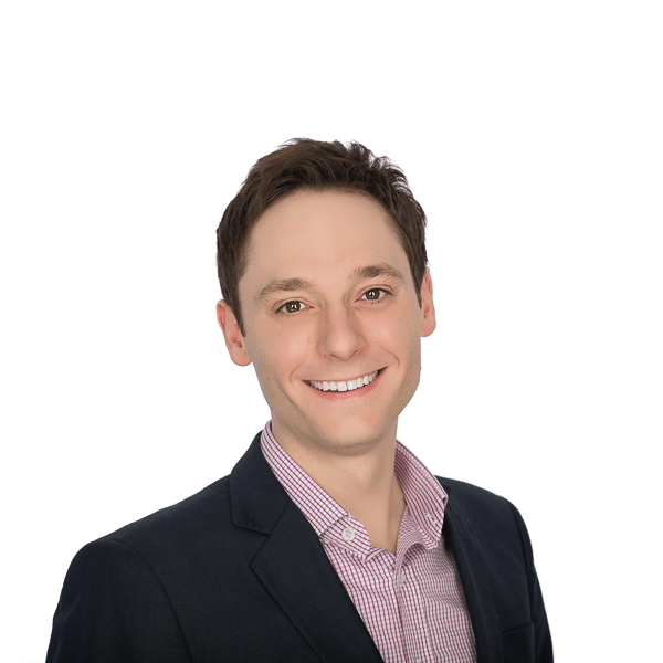 brown haired man in a black jacket and a checkered shirt shirt smiles at the camera