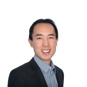 an asian man with black hair in a black jacket and bright blue shirt smiles at the camera