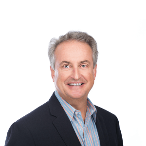 a man with gray hair wearing a black jacket and striped shirt smiles at the camera