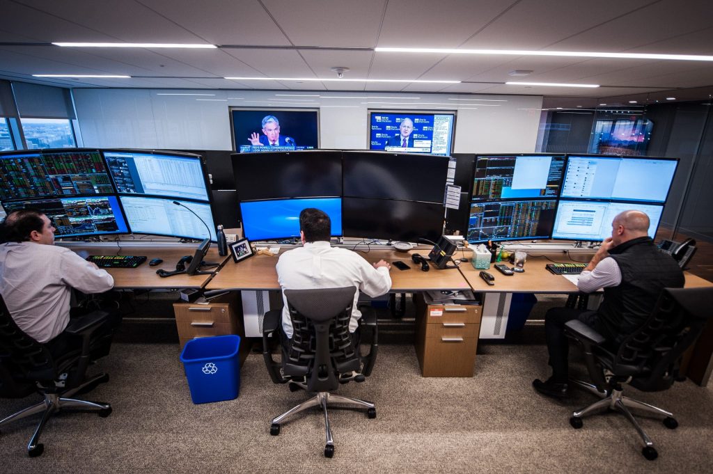 men working at computers with large curved screens