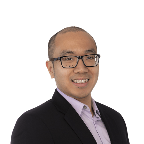 asian man with birthmarks under his eyes in black rimmed glasses wearing a black jacket smiles at the camera