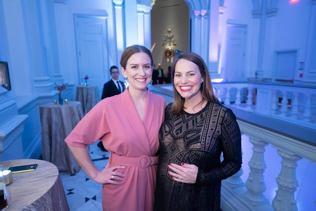 women in dresses are smiling at the camera