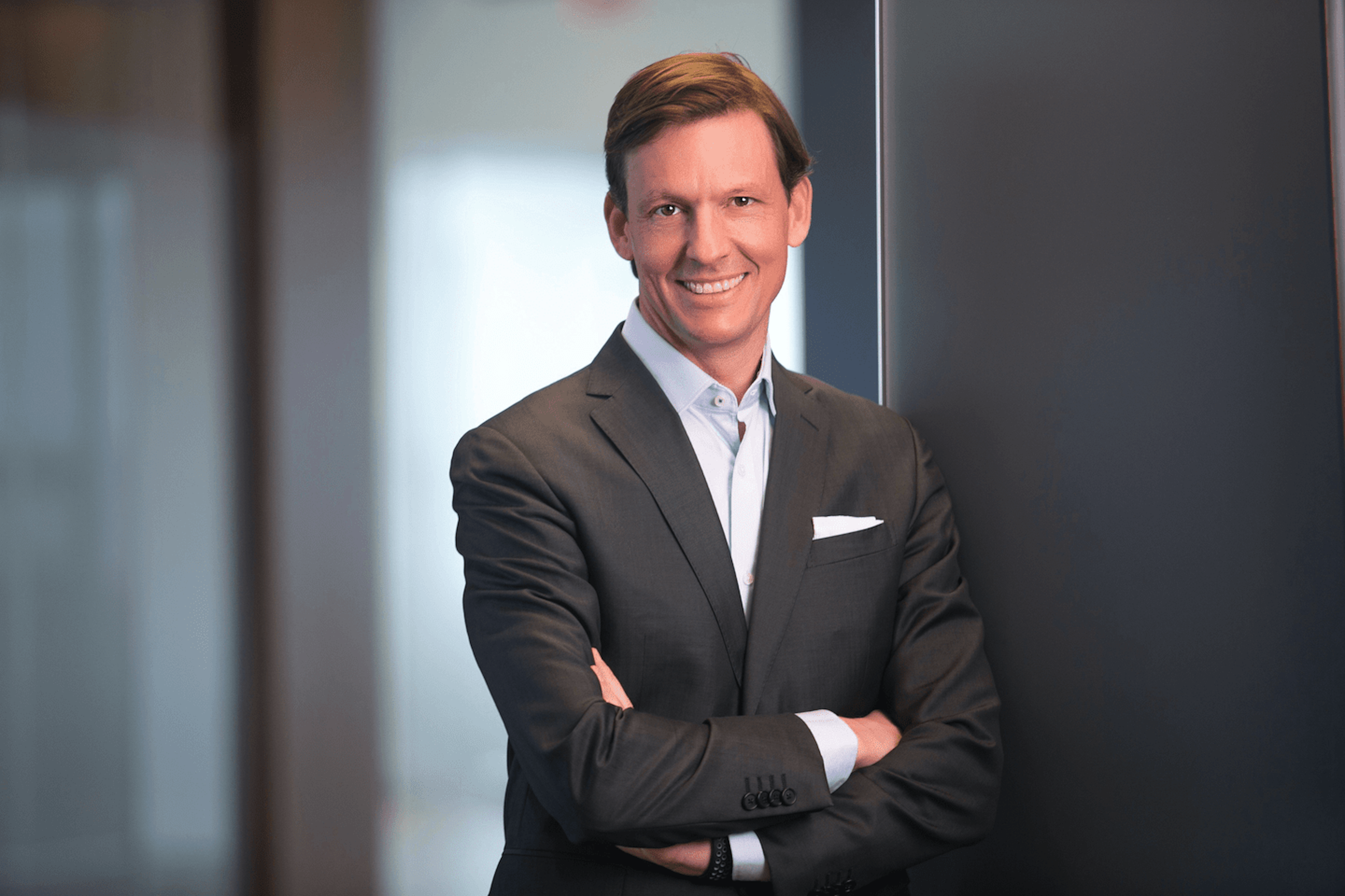 a man in a suit and a blue shirt is smiling at the camera