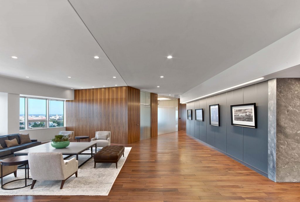 a room with a wooden floor, armchairs and paintings hanging on a graphite wall
