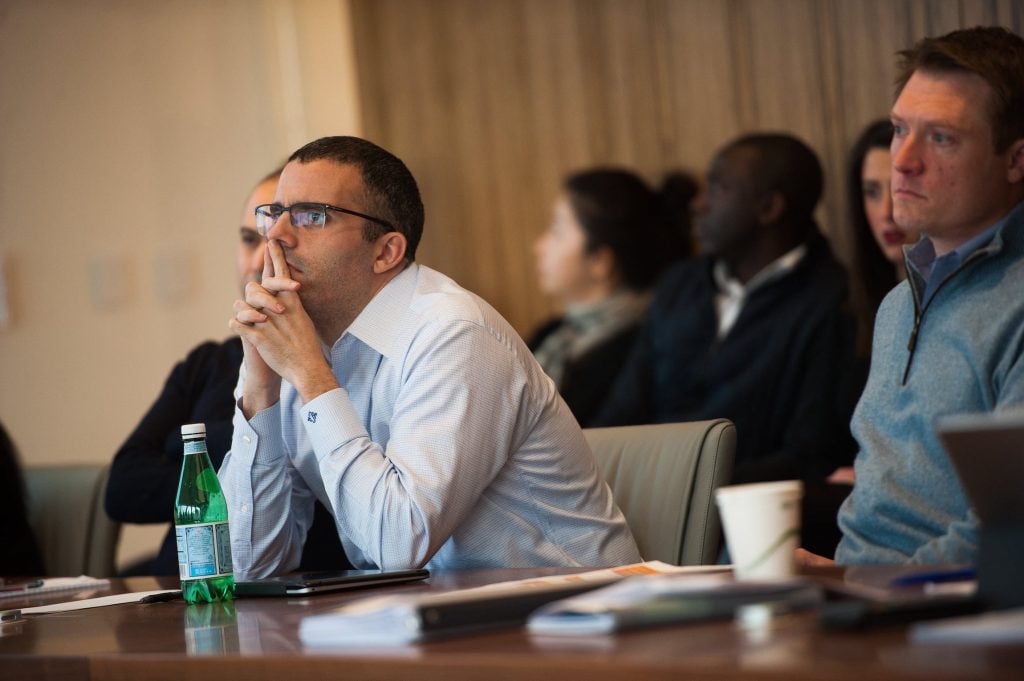 man with glasses sitting at a meeting and listening