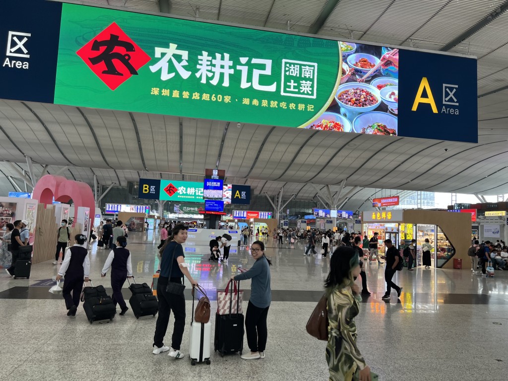 People with suitcases at the airport under the big banner